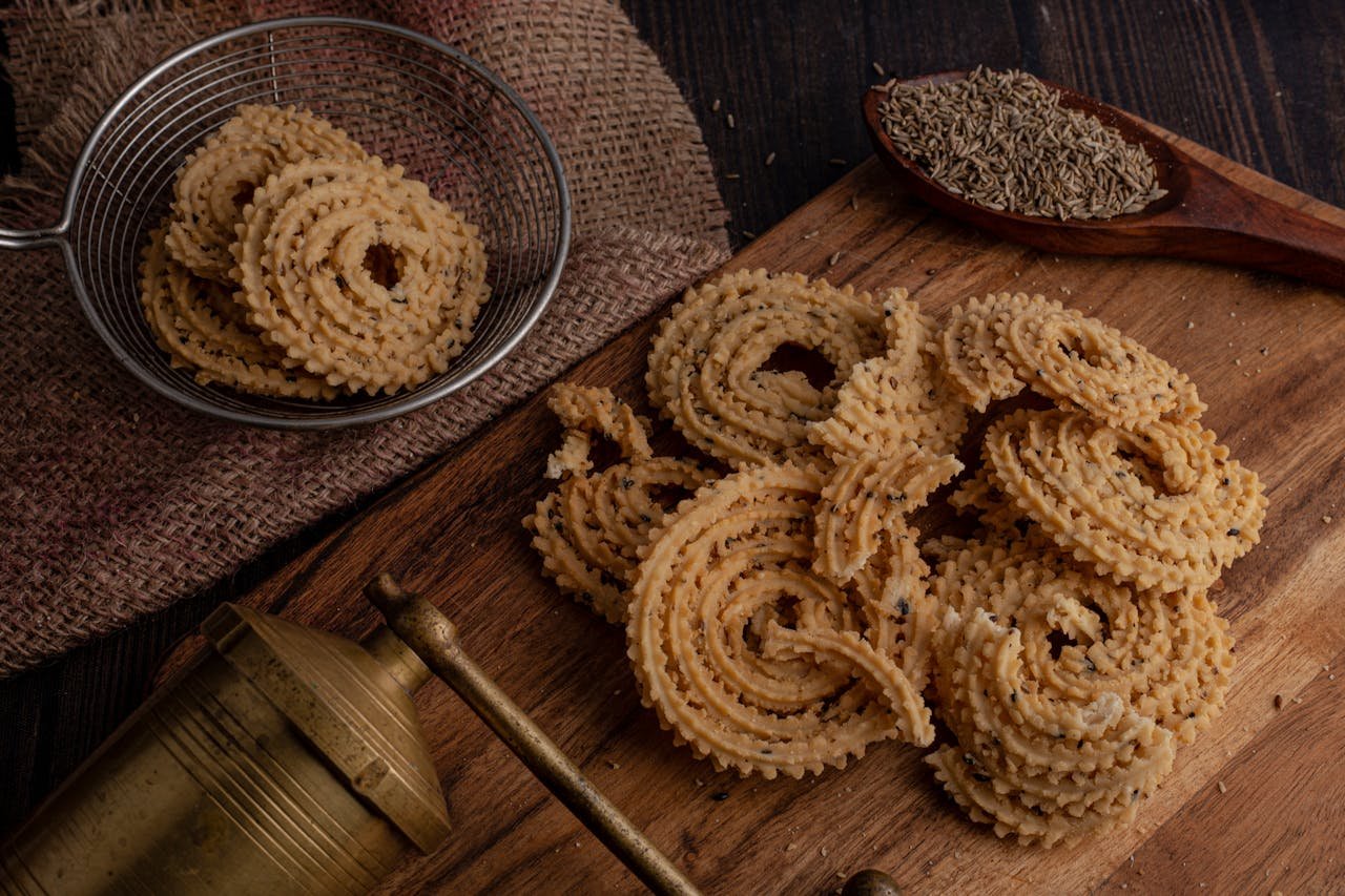 Close-up of crunchy Indian murukku served with cumin seeds on a rustic wooden board.